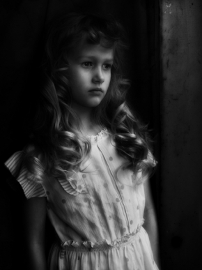 Černobílá fotografie - Dívka vyhlížející z okna